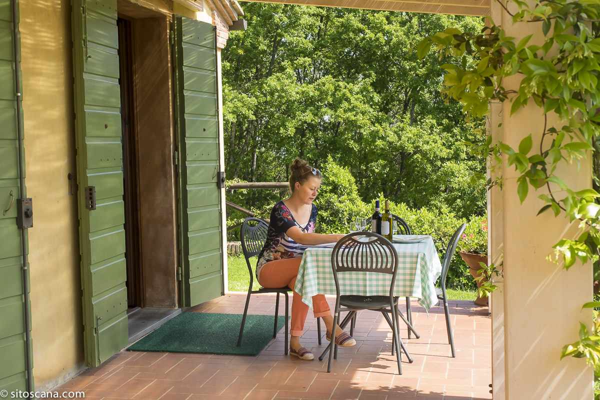 Bildet viser Karine Angell på jobb for SiToscana. Karine sitter å jobber ute på en terrasse i et feriehus i Toscana.
