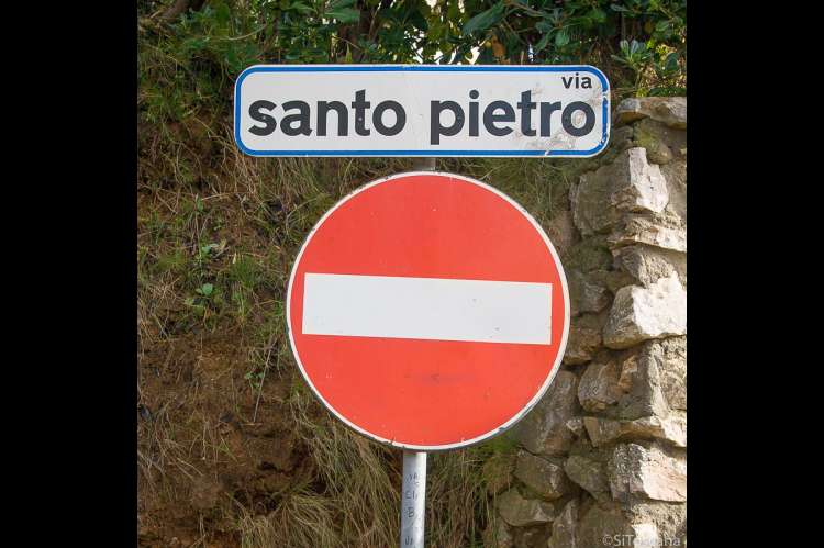 Bildet viser to skilt, ett med gatenavnet Via Santo Pietro og ett med Innkjøring forbudt. Skiltet og veien befinner seg i landsbyen Calci, like utenfor Pisa.