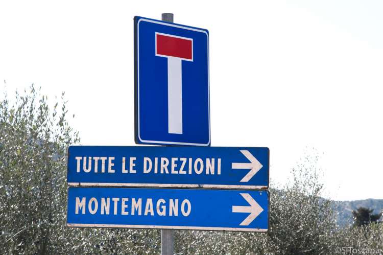 Bildet viser tre skilt. Ett med blindgate. Ett med pil i retning stedet Montemagno. Ett skilt med pil og tekst på italiensk: Tutte le direzioni som betyr Alle retninger.
