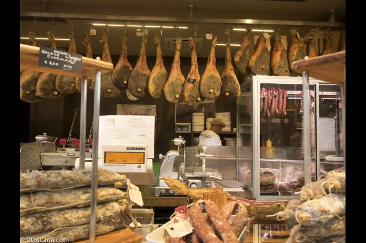 Bildet viser skinker som henger i taket, samt pølser og spekemat lagt opp for salg i Matmarkedet i Firenze – Mercato Centrale