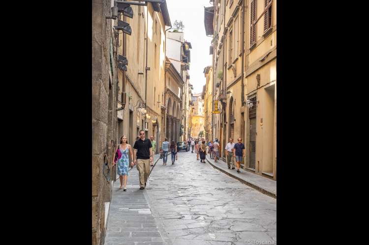 Bildet viser mennesker som går i en rolig gate nesten uten trafikk i Firenze sentrum. I Toscana, i Italia.