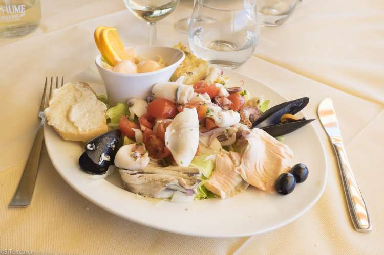 Bildet viser en tallerken med sjømat på en restaurant i Tirrenia i Toscana. På fatet ser du blåskjell, blekksprut, fisk, salat, tomat, løk og oliven.,