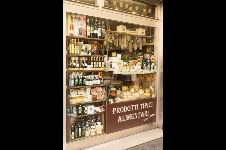 Bildet viser vin, olivenolje og andre godsaker i et utstillingsvindu i en vin- og delikatessebutikk i Lucca.