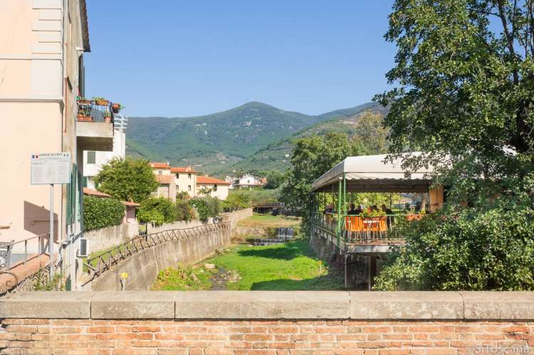 Bildet viser brua over elva Zambra som renner gjennom Calci, like utenfor Pisa. Til høyre ses terrassen til en av barene.