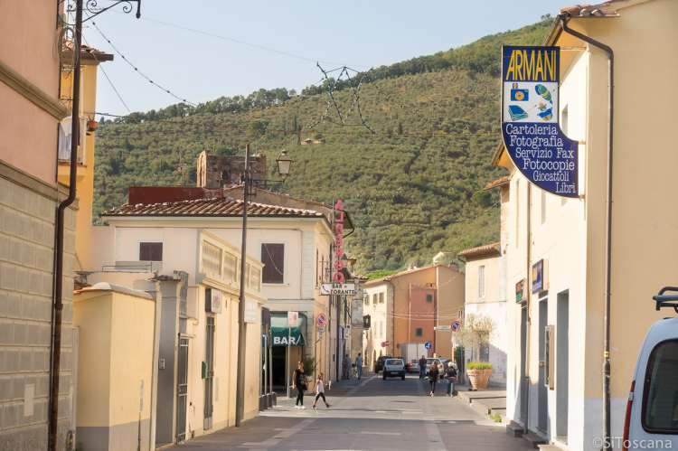 Bildet viser hovedgata Via Roma i Calci. Du ser skiltet til en papirhandel og en bar.