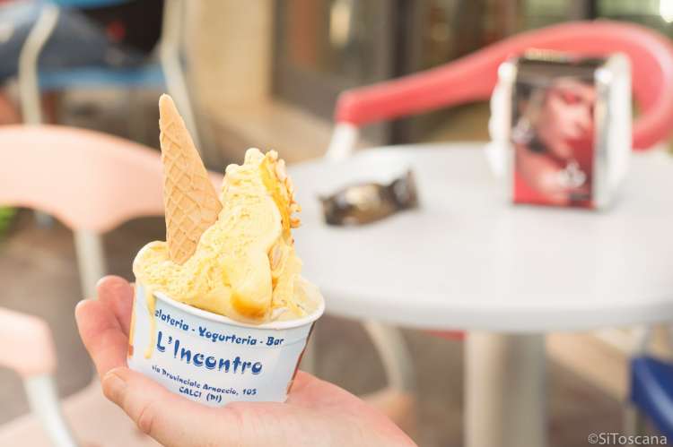 Bildet viser ei hånd som holder et pappbeger med italiensk is på en isbar i landsbyen Calci.