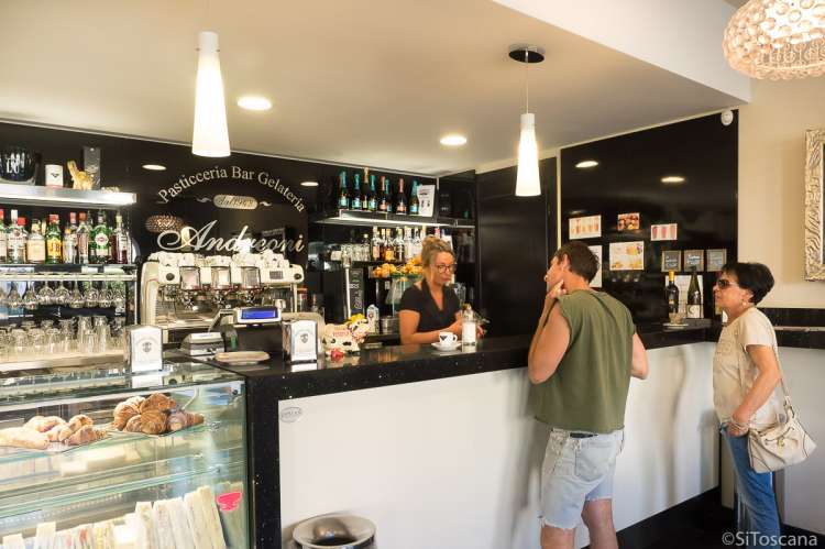 Bildet viser deler av interiøret, en servitør og to kunder i konditoriet Andreoni i Calci.