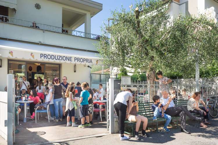 Bildet viser barn som er samlet på en isbar i Calci. De leker, prater og spiser is.