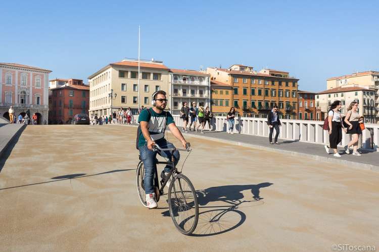 Bildet viser mann som sykler over Ponte di Mezzo i Pisa sentrum en maidag.