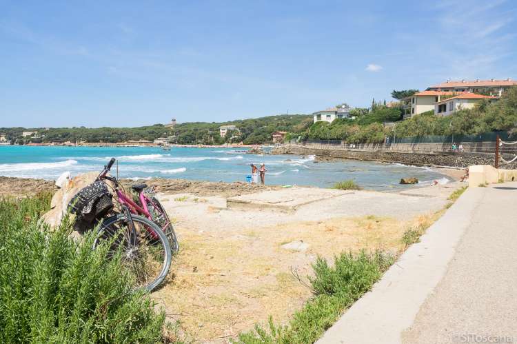 Bildet viser sykkel parkert ved strandpromenaden i Castiglioncello. I bakgrunnen skimtes et par som tørker seg etter å ha bedet i sjøen.
