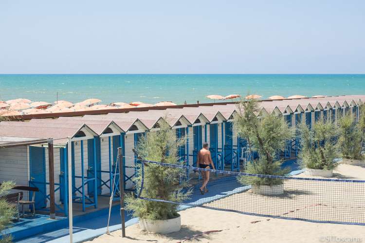 Fra en av bagnoene i badebyen Tirrenia. Badehus eller omskiftingsrom på rekke og rad. Volleyball bane i forgrunnen.