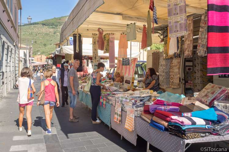 Bildet viser kunder som handler i boden for sengetøy, håndklær og duker på markedet i Calci.