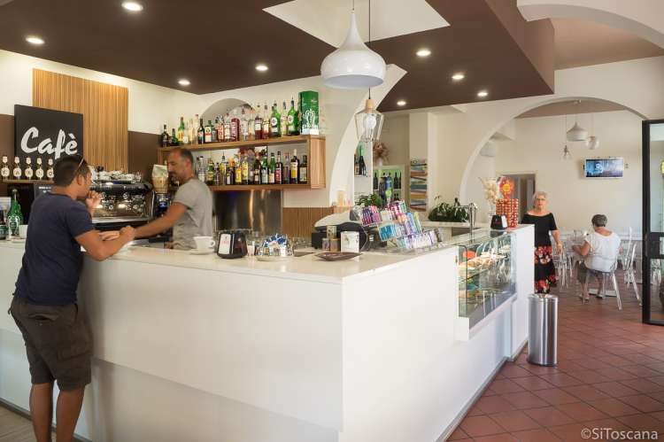 Bildet viser interiøret og servitør og kunde i restauranten og baren Le Gemelle i Calci.