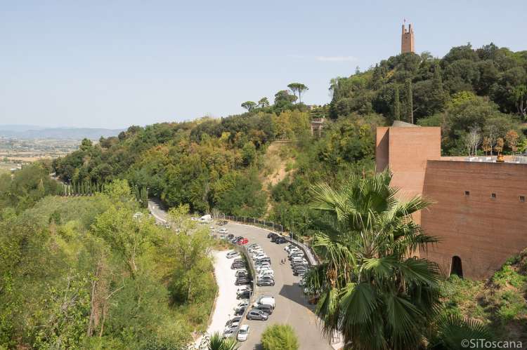 Bildet viser parkeringsplassen utenfor middelalderbyen San Miniato. Huset til høyre inneholder blant annet trapp og heis som fører direkte opp til sentrum. Inne i byen er det begrenset med P-plasser.