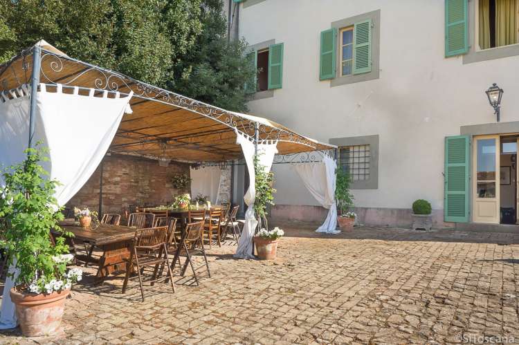 Bildet viser en terrasse med langbord dagen etter en stor bursdagsfeiring i landsbyen Cevoli i Toscana.