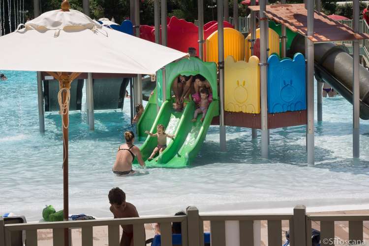 Bildet viser voksne og barn som leker i en av de små vannskliene i barnebassenget på Sunlight Park i Tirrenia. 