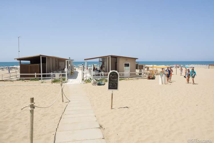 Bildet viser spisestedet og fasilitetene på fristranda Spiaggia Verruca i badebyen Tirrenia i Toscana. Til høyre i bildet sees mennesker på vei opp fra stranda. Stranda med Middelhavet i bakgrunnen. 
