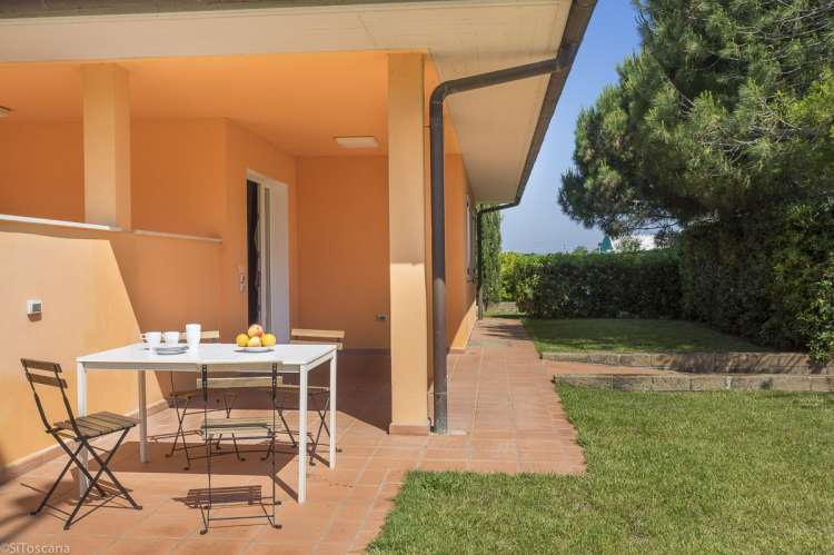 Bildet viser gult hus med uteplass, bord og stoler, til en av leilighetene på Vicino Mare.