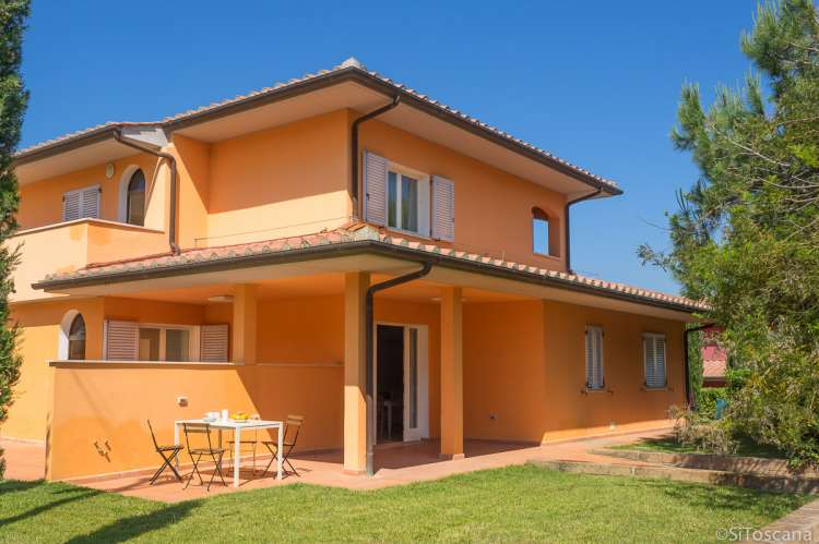 Bildet viser et av husene, oransje, med gressplen på Vicino Mare i gangavstand til strand og landsby. Sør i Toscana.