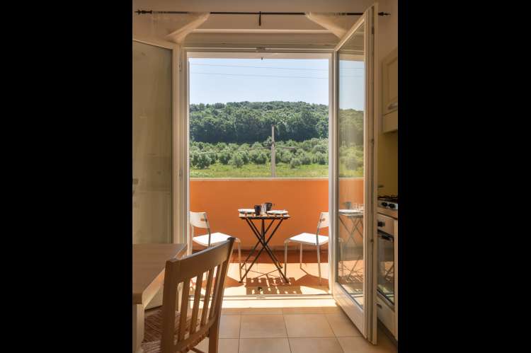 Bildet viser spisebord på kjøkken med utgang til terrasse med utsikt i en av ferieleilighetene på Vicino Mare ved kysten sør i Toscana.