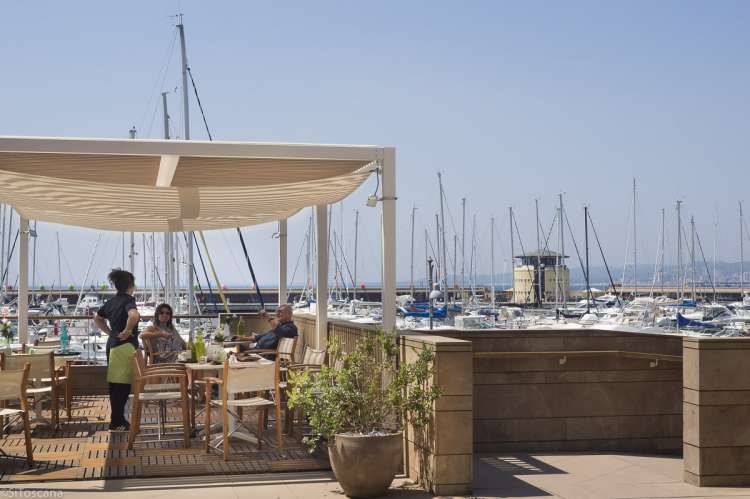 Bildet viser en uterestaurant i den nye havna i gangavstand fra ferieleilighetene på Vicino Mare sør i Toscana.