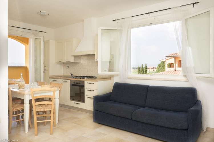 Bildet viser sovesofa i oppholdsrom med utgang til terrasse i en av ferieleilighetene på Vicino Mare ved kysten sør i Toscana.