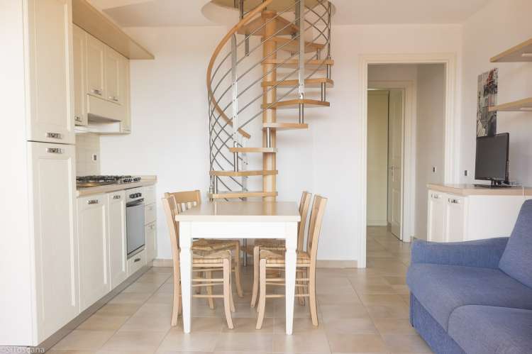 Bildet viser oppholdsrom og kjøkken med spisebord samt sovesofa på Vicino Mare, Grosseto.