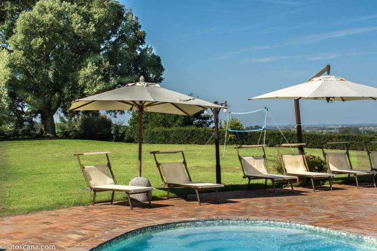 Bildet viser grøntområder rundt bassenget på feriebostedet Volpaia i Toscana. Lekeområde med ballslette i bakgrunnen. Ferie med barn i Italia.
