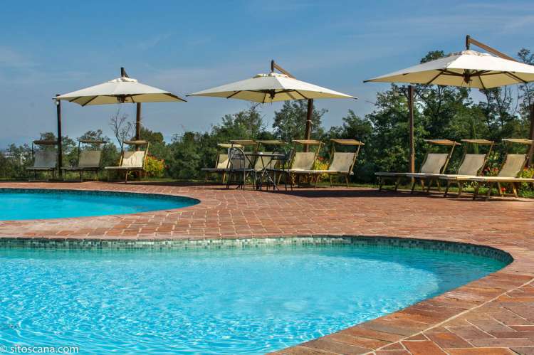 Solsenger og parasoller ved svømmebassenget på feriebostedet Volpaia i Toscana. Eget barnebasseng. Perfekt for familier med barn. Foto.
