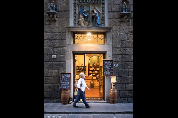 Kvinne som går forbi inngangsdøra til en av vinhandlerne i nærområdet til ferieleiligheten Marco i sentrum av Firenze. Foto.