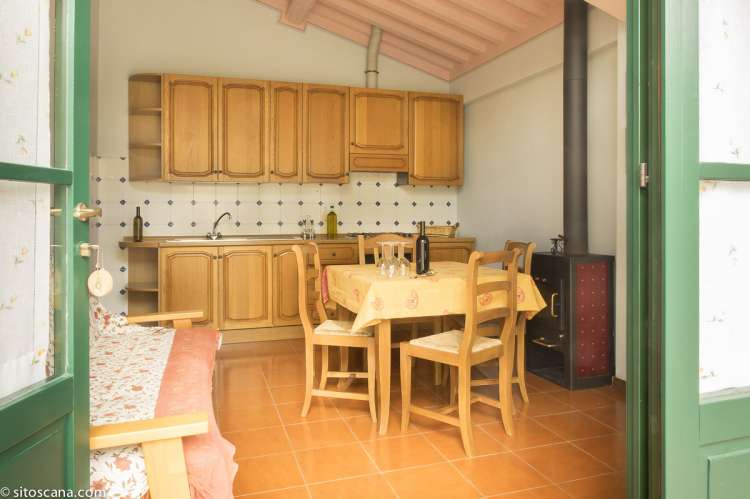 Bildet viser oppholdsrommet med spisebord og sofa samt kjøkken i leiligheten Geranio på feriebostedet Girasole, vingård med 10 leiligheter og gangavstand til landsby.