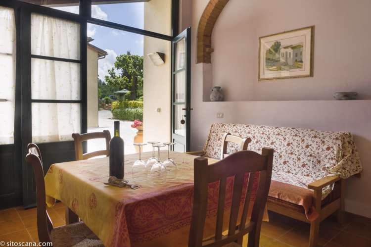 Bildet viser oppholdsrommet med spisebord og sofa samt inngangsdør i leiligheten Geranio på feriebostedet Girasole, vingård med 10 leiligheter og gangavstand til landsby.