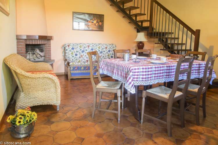 Bildet viser oppholdsrom med spisebord, sofa og peis, samt trapp opp til 2. etg. i leiligheten Melograno på feriebostedet Girasole, vingård med 10 leiligheter og gangavstand til landsby.