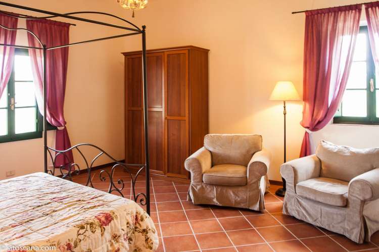 Bildet viser soverom med dobbeltseng og lenestoler i leiligheten Glicine på feriebostedet Girasole, vingård med 10 leiligheter og gangavstand til landsby.