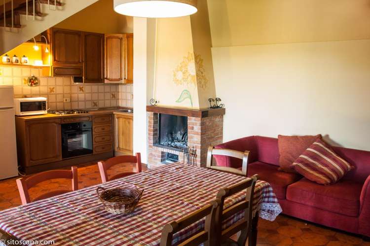 Bildet viser oppholdsrom med spisebord, kjøkken, peis og trapp opp til 2. etg. i leiligheten Girasole på feriebostedet Girasole, vingård med 10 leiligheter og gangavstand til landsby.