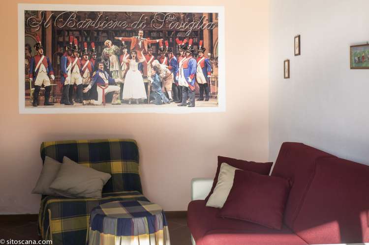 Oppholdsrom med sovesofa i suite med soverom på hems. Oppholdsrom med sofa og lenestol i suite på vingården Podere Cenni ved San Miniato. Foto.