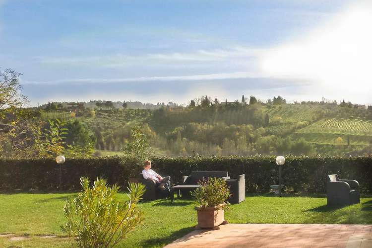 En dag i november på Podere Cenni. Kvinne som slapper av i hagestol og nyter utsikten på vingården Podere Cenni utenfor San Miniato. Foto.