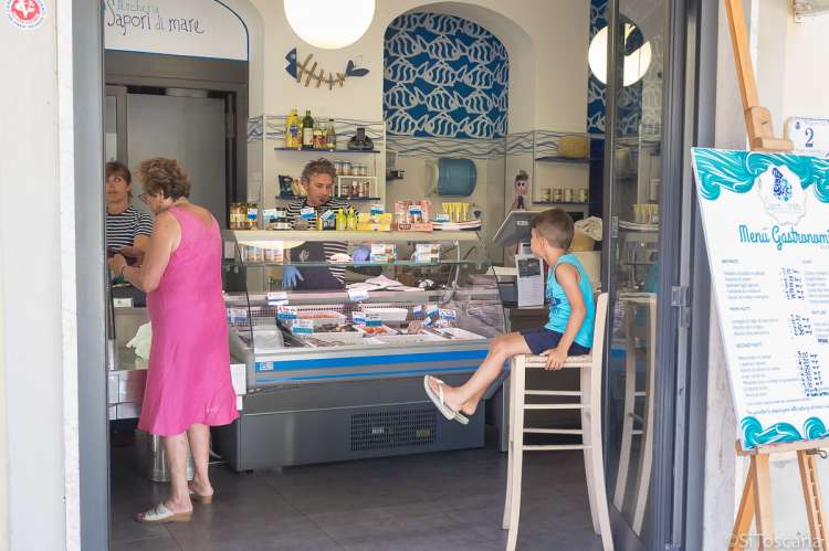 I sentrum (400 m) er det blant annet fiskebutikk med ferske varer og egenproduserte fiskeretter til take-away. Bildet viser fiskebutikk i sentrum av badebyen Vada sør for Pisa i Italia.