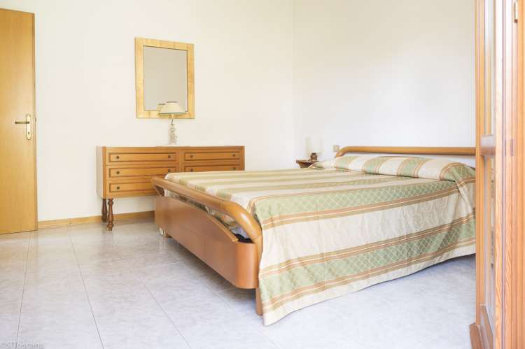 Bildet viser soverom med dobbeltseng og utgang  til uteplass i hagen i ferieboligen Vito al Mare i badebyen Castiglioncello.