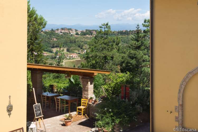 Restauranten har utsikt til middelalderbyen San Miniato (3,5 km). Bilde av uteplass med utsikt mellom husene på vingården.