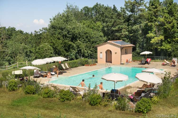 På bildet ser man voksne og barn som koser seg ved bassenget på vingården.