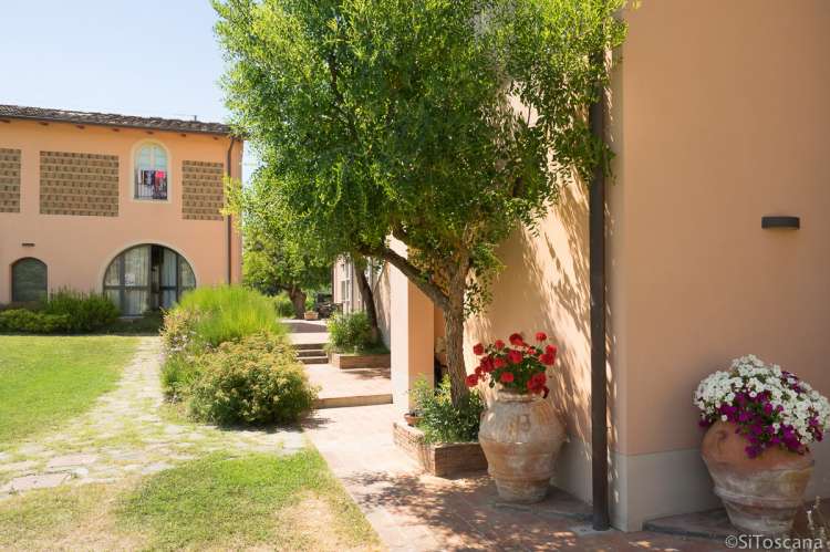 Foto viser de velholdte gangveiene rundt om på vingården. Blomster i krukker.
