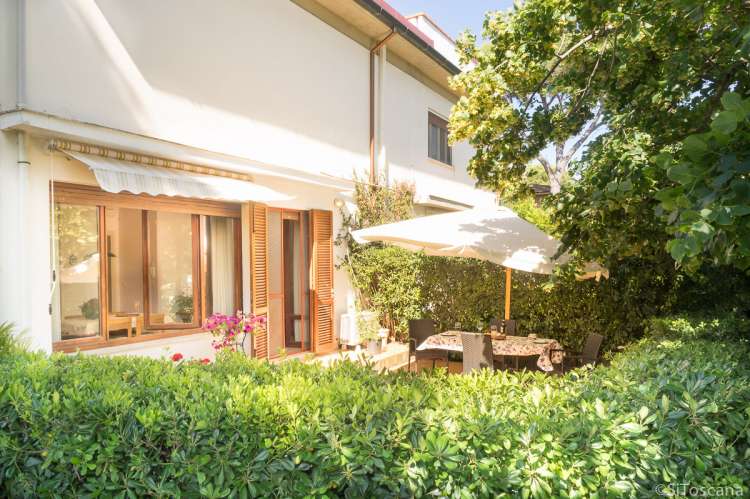 Bildet viser inngangspartiet til ferieleiligheten Marco i Buganvilla ved havet. Spisebord under parasoll.