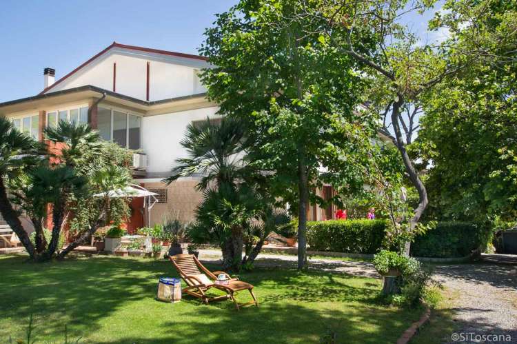 Bildet viser feriehuset Buganvilla med frodig hage, blomster og trær.