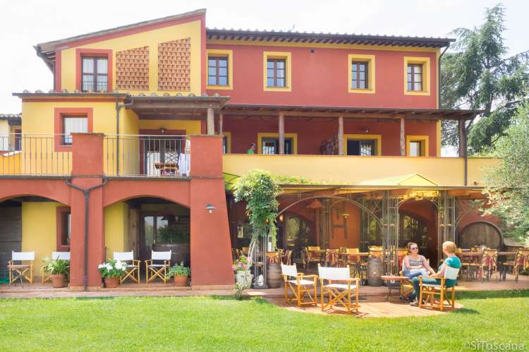 Bildet viser to kvinner som sitter på uteserveringen foran restauranten på feriebostedet La Pergola, ved Pisa i Toscana.