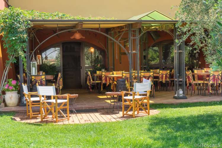 Bildet viser bord og stoler i solskinn, på uteserveringen foran restauranten på feriebostedet La Pergola, nært Pisa i Toscana.