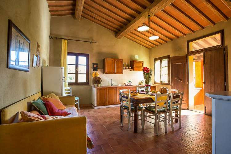 Bildet viser oppholdsrom med kjøkken, spisebord, sofa og inngangsdør i ferieleiligheten Nespola på La Pergola i Toscana.