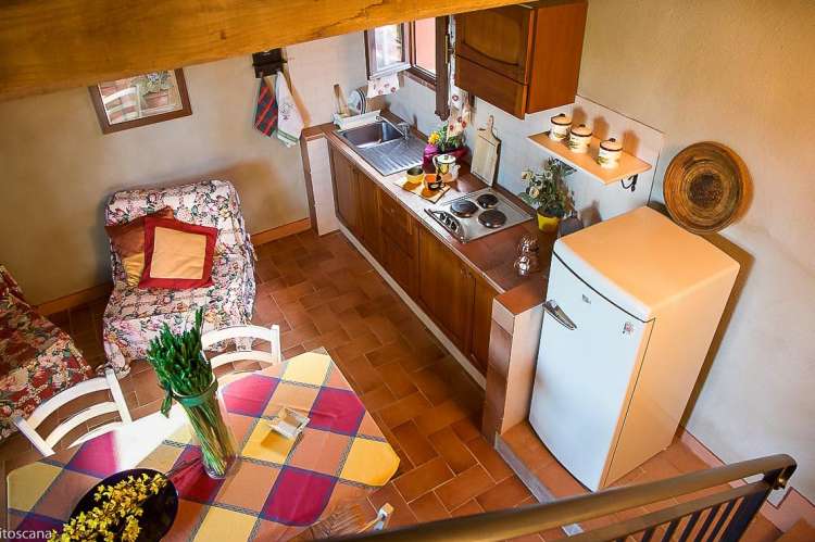 Bildet viser kjøkken med spisebord og kjøkkenbenker. Tatt fra trappa opp mot soverommet i 2. etg. I ferieleiligheten Fragola på La Pergola i Toscana.