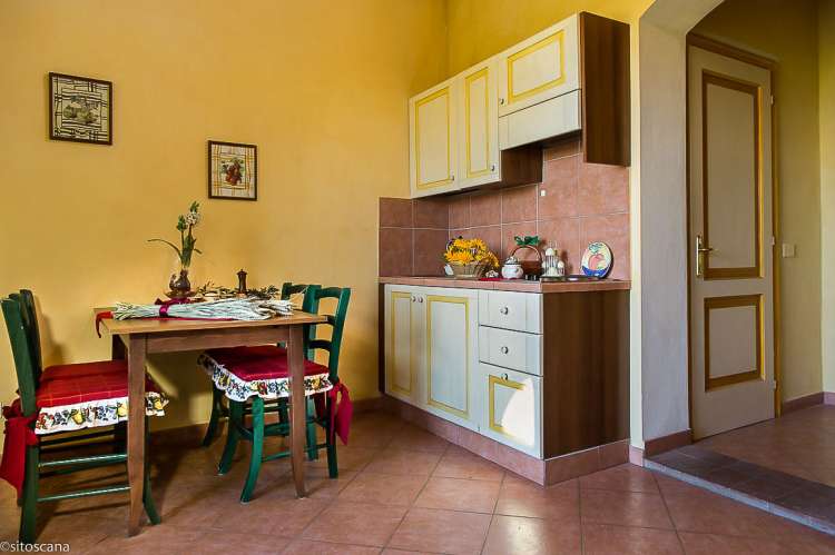 Bildet viser oppholdsrom med spisebord og utgang i ferieleiligheten Ciliegia. På feriebostedet La Pergola ved landsby i Toscana.