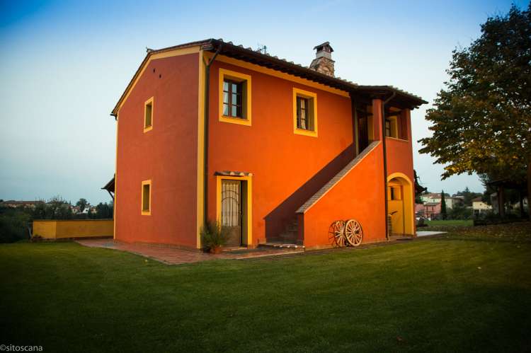 Bildet viser et av husene på La Pergola i kveldssol. Nederst til venstre ligger døra inn til leiligheten Lampone. Trappa fører opp til leiligheten Nespola. På feriebostedet La Pergola i Toscana. 